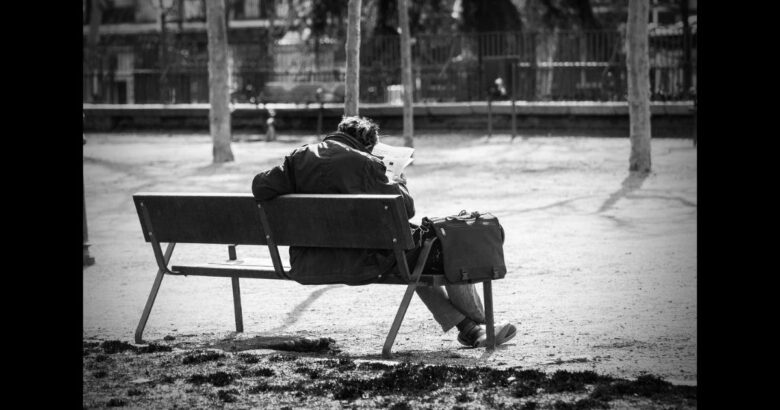 公園のベンチで新聞を読む男性